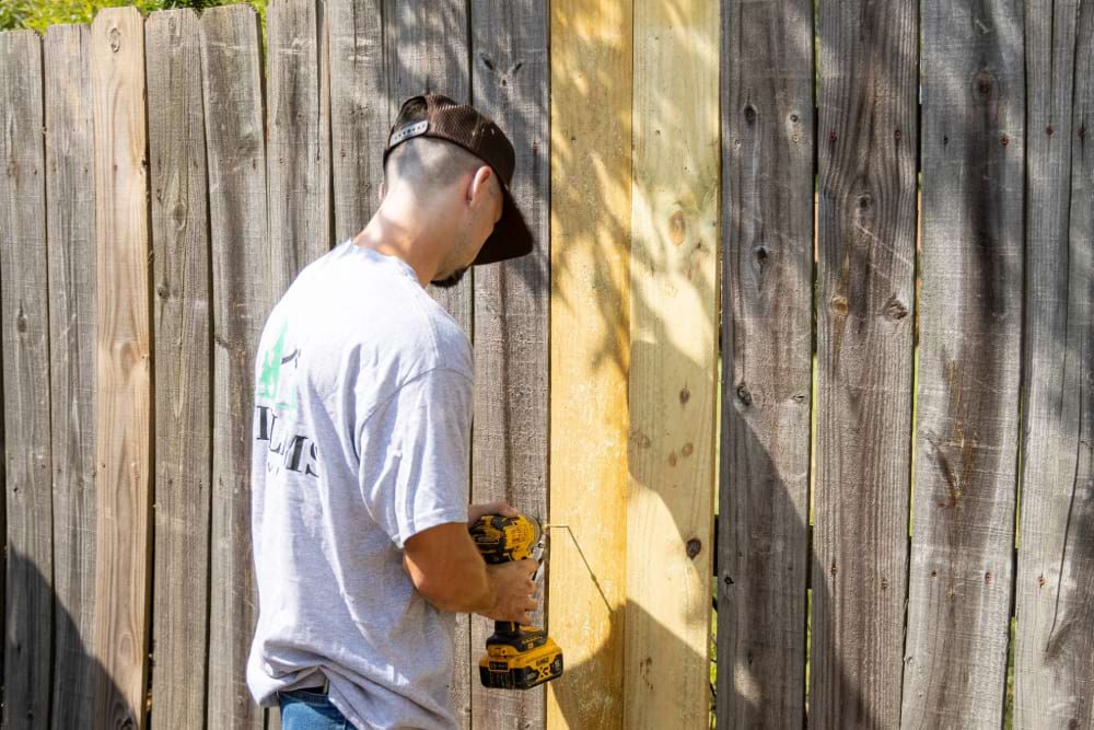 Williams services worker fixing a fence