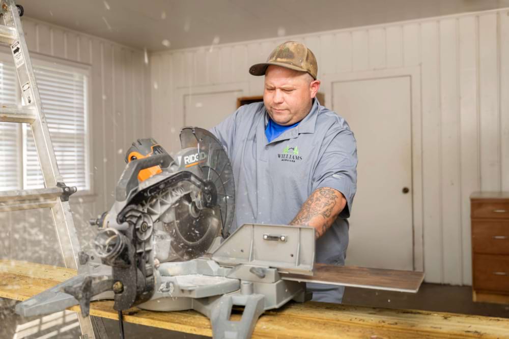 Williams services worker power sawing through flooring