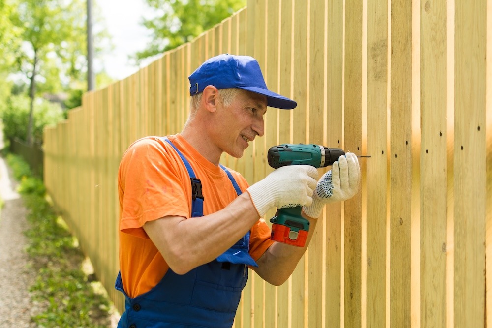 middle aged male screwing in a wooden fence
